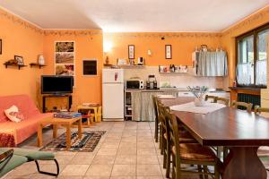 a kitchen and dining room with a table and a kitchen with a refrigerator at Casa Vacanze il Ginepro in Sinio