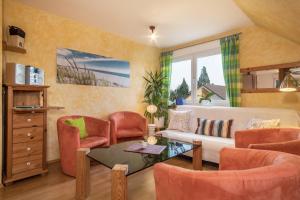 a living room with orange chairs and a white couch at Ferienwohnung Tasoli in Lindau