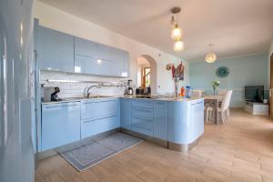a large kitchen with blue cabinets and a table at Villa Felicità in Sorso