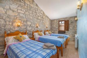 a bedroom with three beds and a stone wall at Ca La Pascola in Guimerá