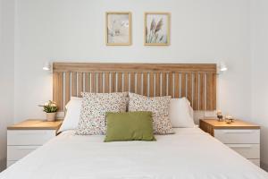 a bedroom with a white bed with a wooden headboard at Horus Beach Paradise in Torre del Mar +14 photos