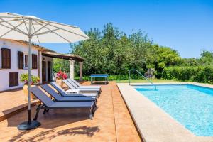 a pool with chairs and an umbrella next to a house at Can Amer in Pollença