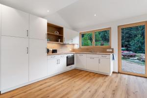 a kitchen with white cabinets and a wooden floor at Ferienwohnung Burgblick in Biberach
