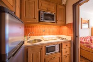 a small kitchen with a sink and a microwave at Serre-chevalier Vallée - Briançon in Briançon +16 photos