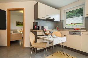 a kitchen with white cabinets and a table and chairs at Haus Afaldra in Mengen +16 photos