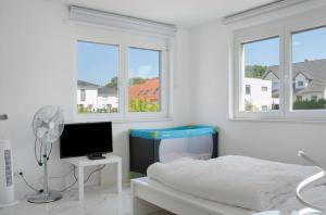 a white bedroom with a bed and a tv at Luxusvilla Neubau 1 in Oberasbach