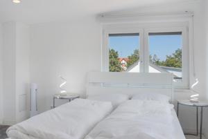 a white bedroom with a white bed and two tables at Luxusvilla Neubau 1 in Oberasbach