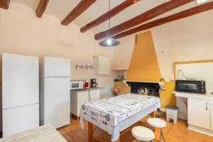 a kitchen with a table and a white refrigerator at Masia Cal Vies in Castellví de la Marca