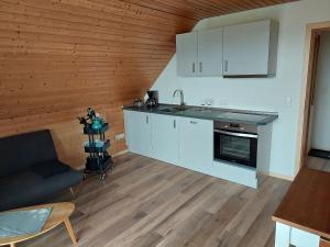 a kitchen with white cabinets and a couch in a room at Ferienwohnung Reinbold in Durbach