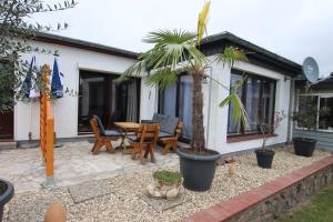 a patio with a table and chairs and a palm tree at Haus Meereswelle in Büsum