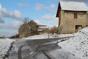 a snow covered road next to a stone building at Gîte Chez Claudette in Briord