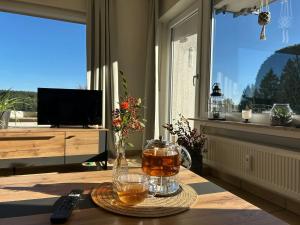 a table with a vase and drinks on it in a living room at Tannenblick in Schönwald