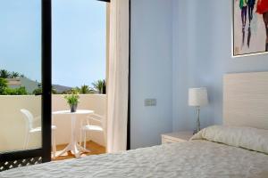 a bedroom with a bed and a balcony with a table at Villa Pueblo Don Thomas in Playa de Santiago +21 photos