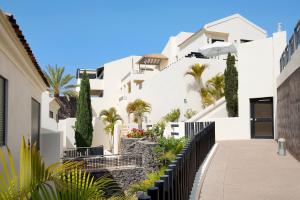 a white building with palm trees and a sidewalk at Villa Pueblo Don Thomas in Playa de Santiago