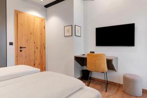 a bedroom with a desk and a television on the wall at Residence Skutial Santner Deluxe in Castelrotto