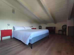 a bedroom with a large white bed and a wooden floor at Gnazzano Home in Loiano