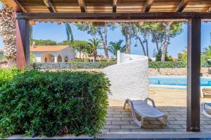 a patio with a chair and a hedge and a pool at Bes Beach - Villa con piscina in Fontane Bianche