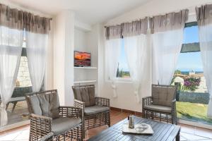a living room with chairs and a table and windows at Li Conchi 34 in Castiadas