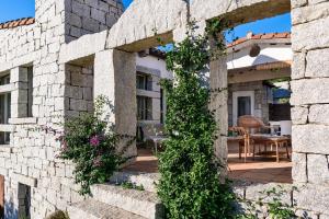 a house with a stone wall and ivy at Li Conchi 34 in Castiadas