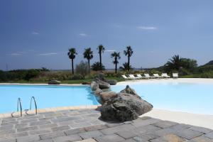 a large swimming pool with rocks in front of it at Li Conchi 34 in Castiadas