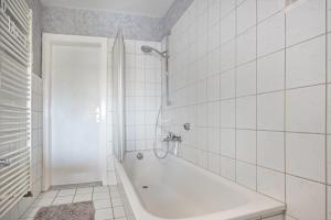 a white tiled bathroom with a tub and a shower at Schöner Ith Blick in Salzhemmendorf +17 photos