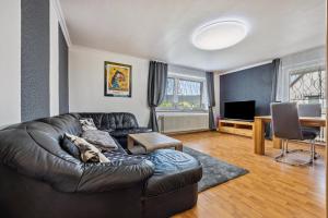 a living room with a leather couch and a television at Schöner Ith Blick in Salzhemmendorf