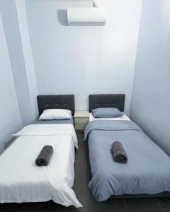 two beds in a room with white walls at Kanvas 21 in Jerantut