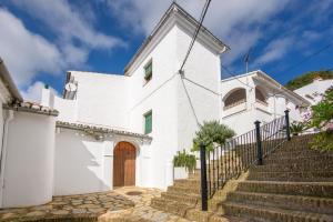 a white church with a wooden door and stairs at La Casa De Eva in Gaucín +21 photos