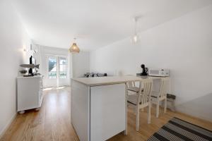 a white kitchen with a counter and a table at Casa da Praia in Praia de Odeceixe