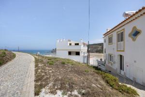 a building on the side of a road next to the ocean at Casa da Praia in Praia de Odeceixe