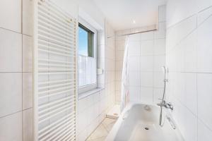 a white bathroom with a tub and a window at Ferienhaus Knappstein in Möhnesee +27 photos
