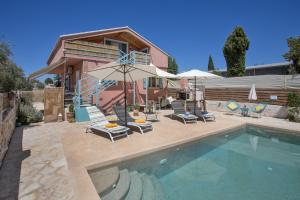 a house with a swimming pool with chairs and umbrellas at Zante Villa Amici Loft in Zakynthos