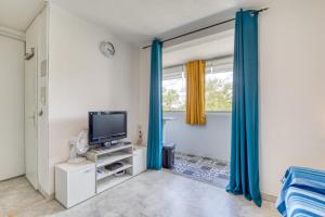 a living room with a television and blue curtains at Le Cosy à la grande pyramide in La Grande Motte