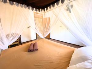 a pair of sandals sitting on a bed in a bedroom at Santai Surf Lodge-Balangan in Uluwatu