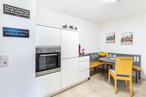 a kitchen with white cabinets and a table with yellow chairs at Ferienwohnung Geisbergblick in Seelbach