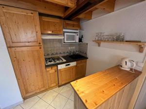 a kitchen with wooden cabinets and a stove top oven at Charmant Duplex Pied De Pistes in Briançon +3 photos