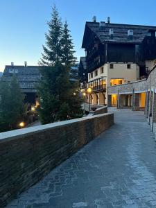 a stone walkway next to a building with a tree at Ninette, intimità e natura in Sauze di Cesana