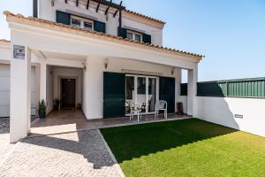 a white house with a patio with a table and chairs at Casa d' Ana in Sesimbra