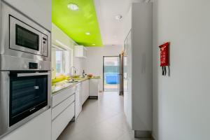 a kitchen with white cabinets and a green ceiling at Casa d' Ana in Sesimbra