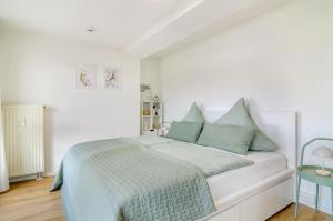a white bedroom with a bed with blue pillows at Ferienapartment Olivia in Bodman-Ludwigshafen +11 photos