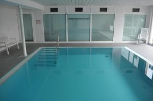 a large swimming pool with blue water in a building at Ferienapartment Olivia in Bodman-Ludwigshafen