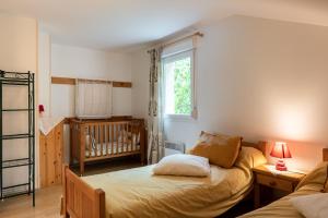 a bedroom with a bed and a crib and a window at Gite La Sabaudia in Gérardmer