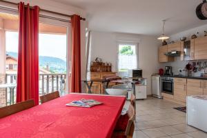 a kitchen with a red table and a kitchen with a balcony at Gite La Sabaudia in Gérardmer