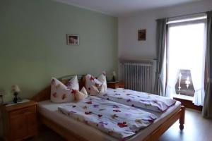 a bedroom with a bed with white sheets and a window at Ferienwohnung Zugspitze in Grainau +2 photos