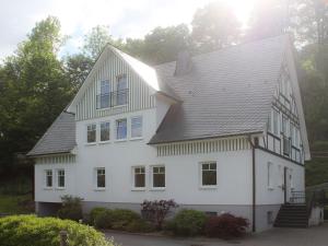 a white house with a gambrel roof at Ferienwohnung Am Lennepark in Schmallenberg