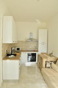 a kitchen with white cabinets and a table and a couch at Domus Teresa in Capoterra +6 photos
