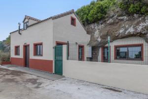 a white building with red doors next to a hill at Casa Efrén in Garafía