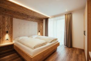 a bedroom with a large bed and a large window at Chalet La Flüta Viola in La Valle