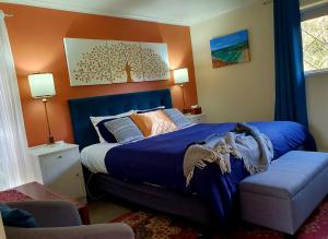 a bedroom with a blue bed and a tree painting on the wall at Oaktree Guest House in Narbethong +122 photos