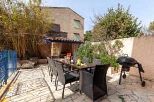 a patio with a grill and a table and chairs at Villa L'Acanthe in Six-Fours-les-Plages